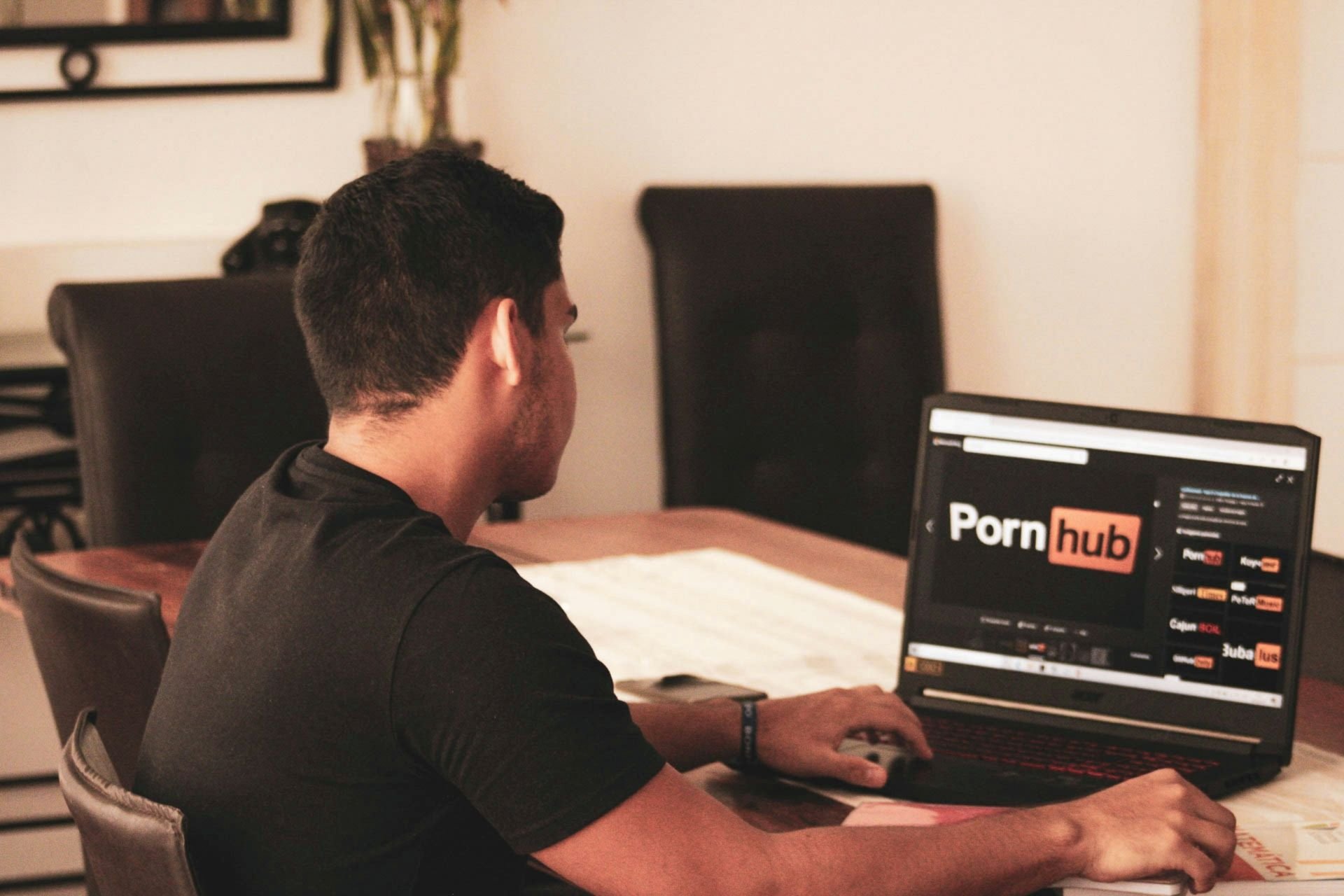 Foto de um homem de costas acessando o Pornhub em um notebook
