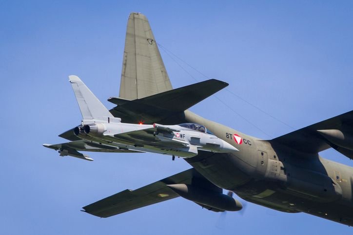 aviao-c-130-hercules-voando-ao-lado-de-um-caca