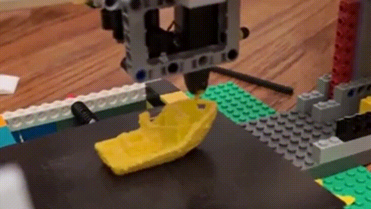 Gif animado mostra uma impressora 3D feita com peças de Lego criando um objeto de plástico