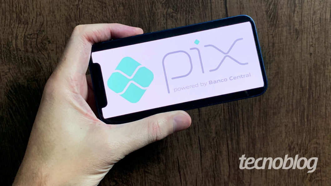 Imagem mostra um iPhone com o logo do Pix na tela. Na parte inferior direita, o logotipo do "tecnoblog" é visível.