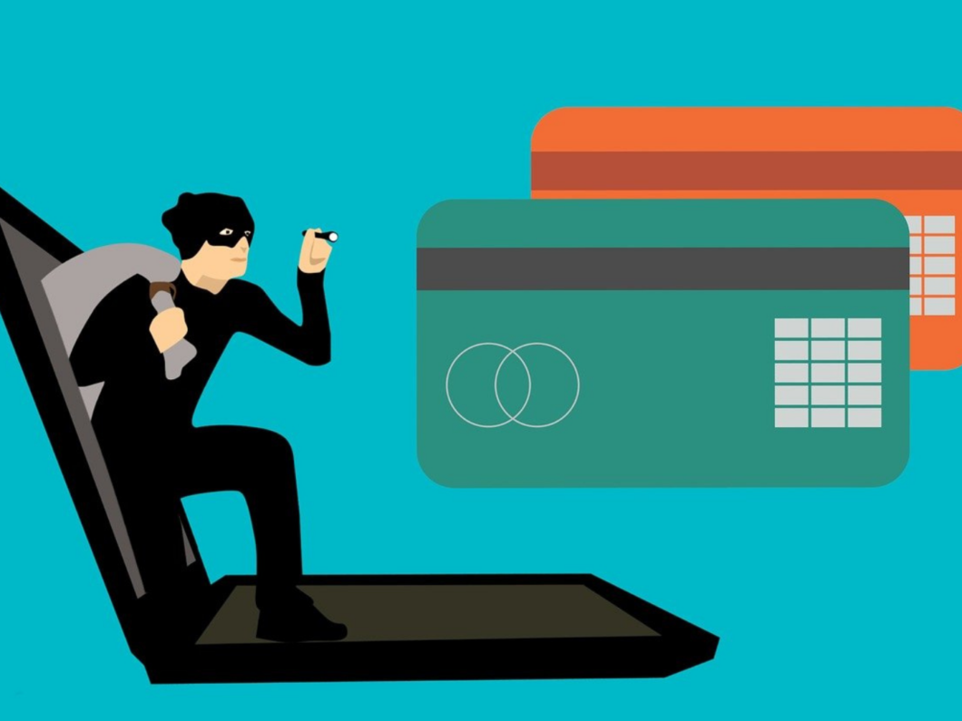 Ilustração de golpe de phishing mostra uma pessoa com máscara saindo de um computador, carregando uma sacola. À direita, dois cartões de crédito. 
