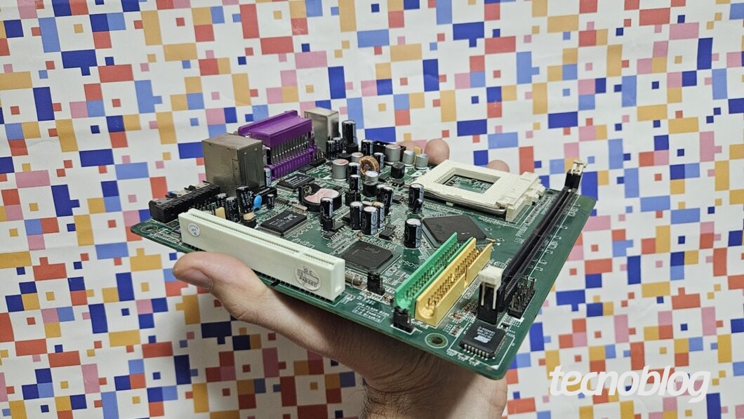 Mão segurando placa mãe sobre fundo abstrato