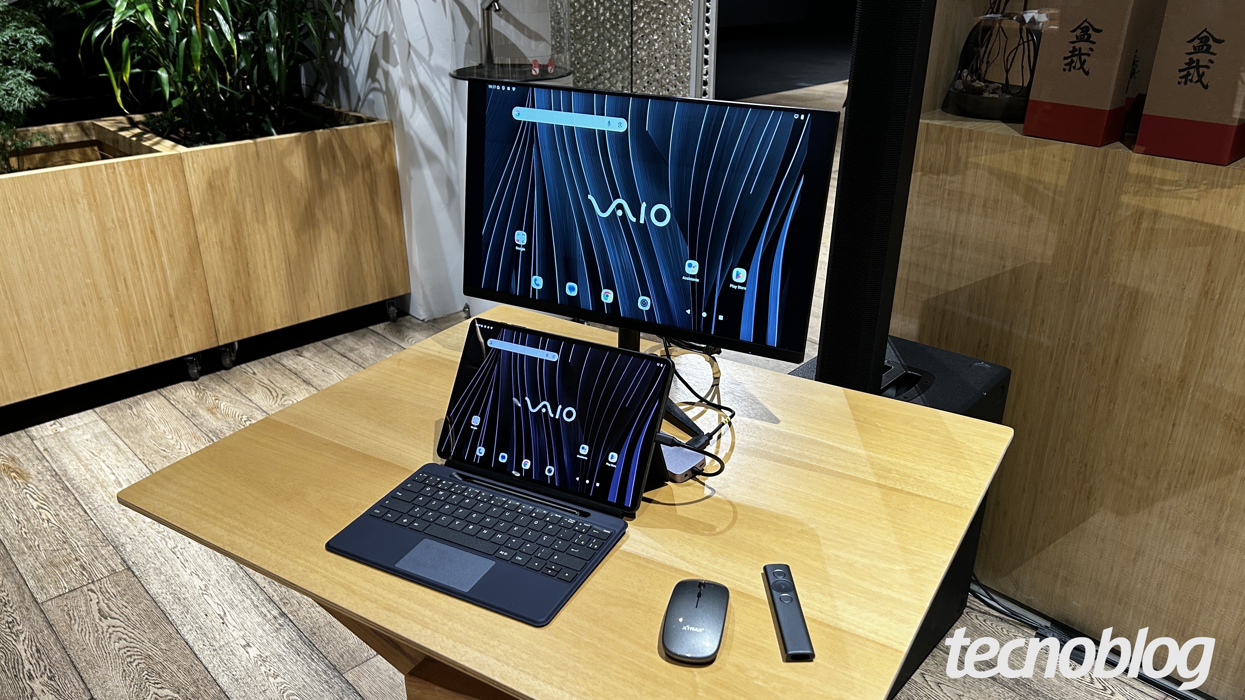 Imagem mostra um tablet Vaio TL12 sobre uma mesa de madeira. Ele é de cor preta e está sendo usado como desktop, com mouse e monitor acoplados. Na parte inferior direita, a marca d'água do "tecnoblog" é visível.