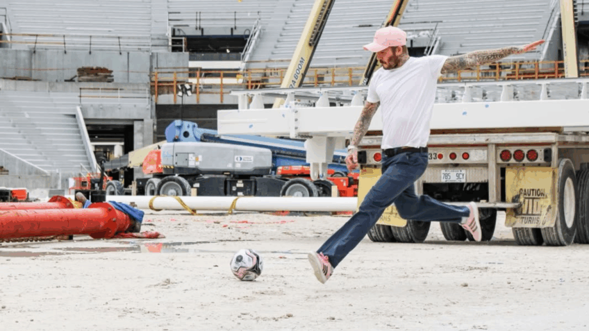 Beckham chutando a bola no lugar onde será o gramado do novo estadio